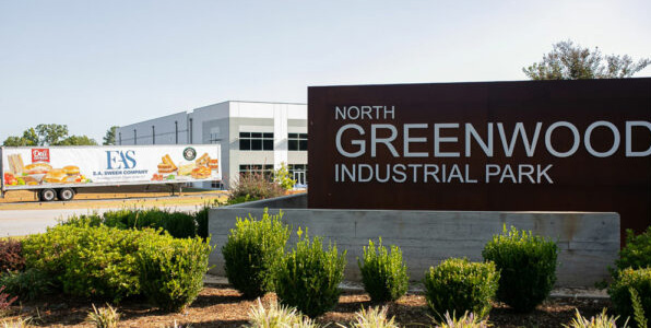 North Greenwood Industrial Park sign in foreground with E.A.Sween tractor trailer backing up to E.A.Sween manufacturing facility behind